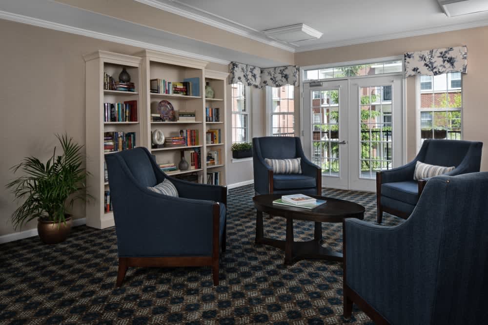 A cozy living room with blue armchairs and bookshelves by the window.