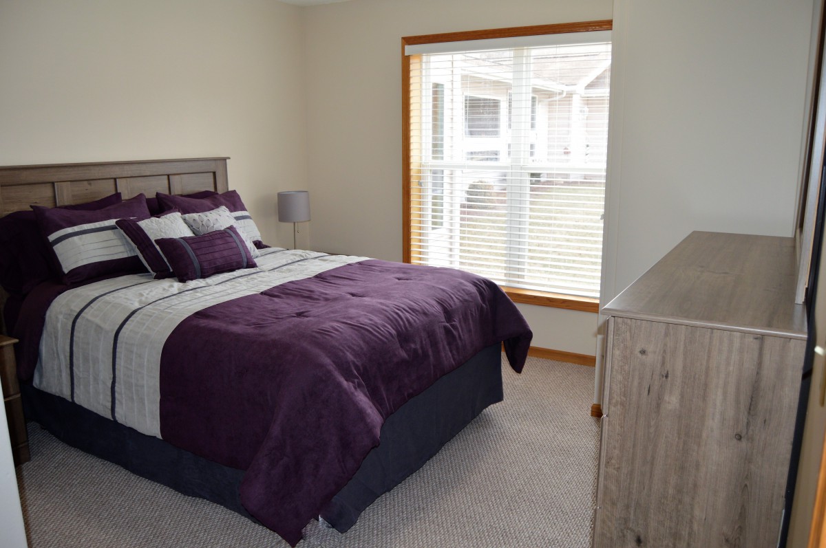 A cozy bedroom with a neatly made bed and a large window.