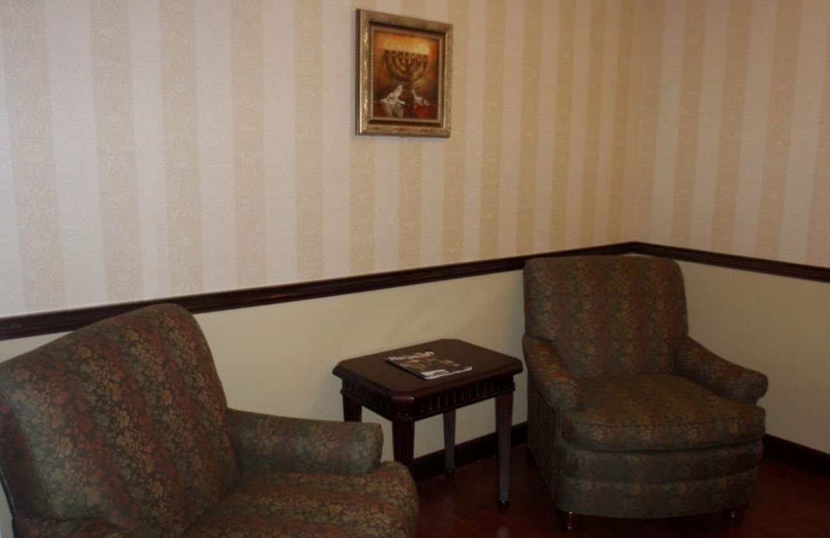 A cozy living room setup with two chairs, a small wooden table, and a painting on the wall.