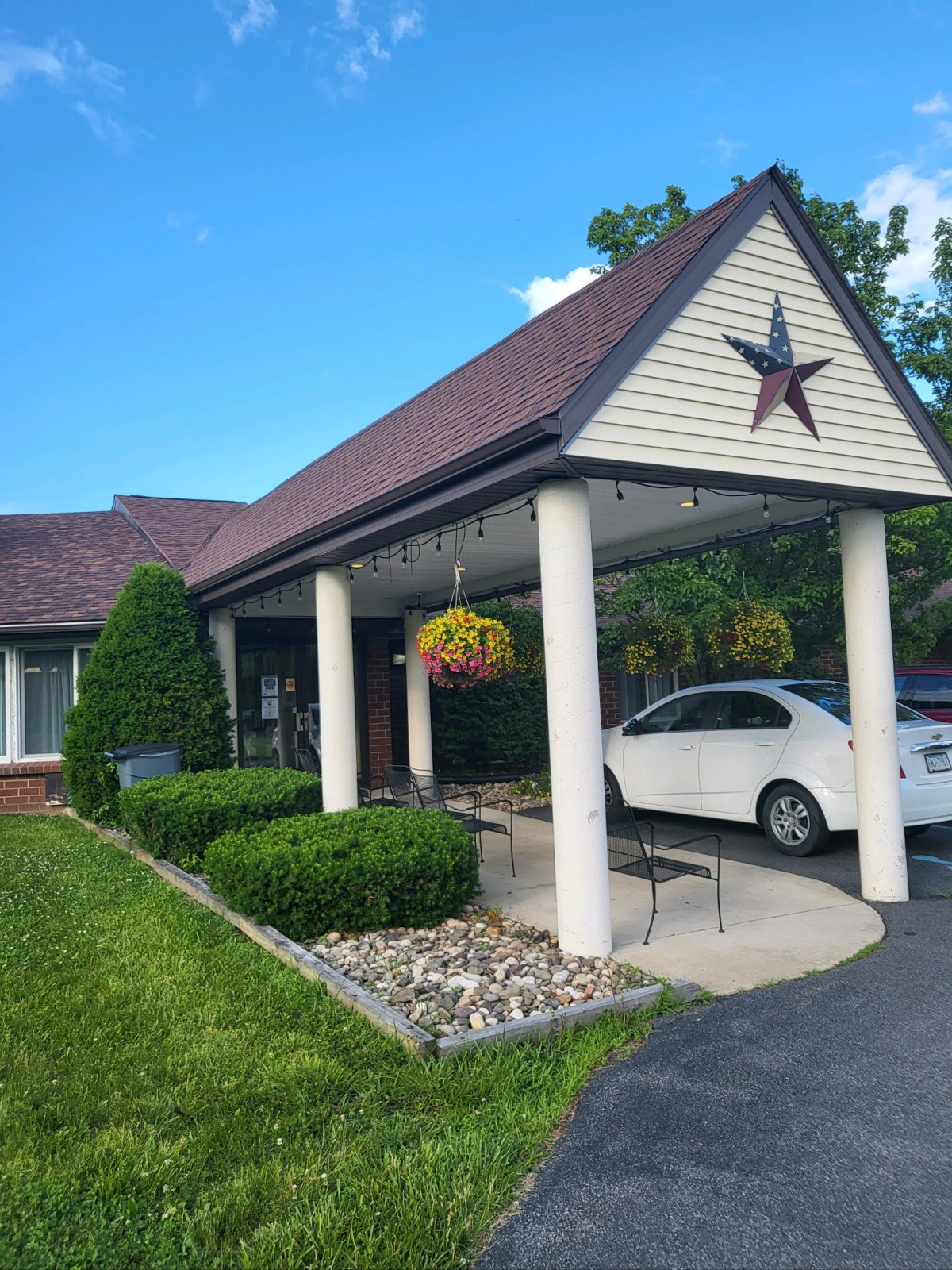 A building entrance with a driveway, featuring a hanging plant and star decoration.
