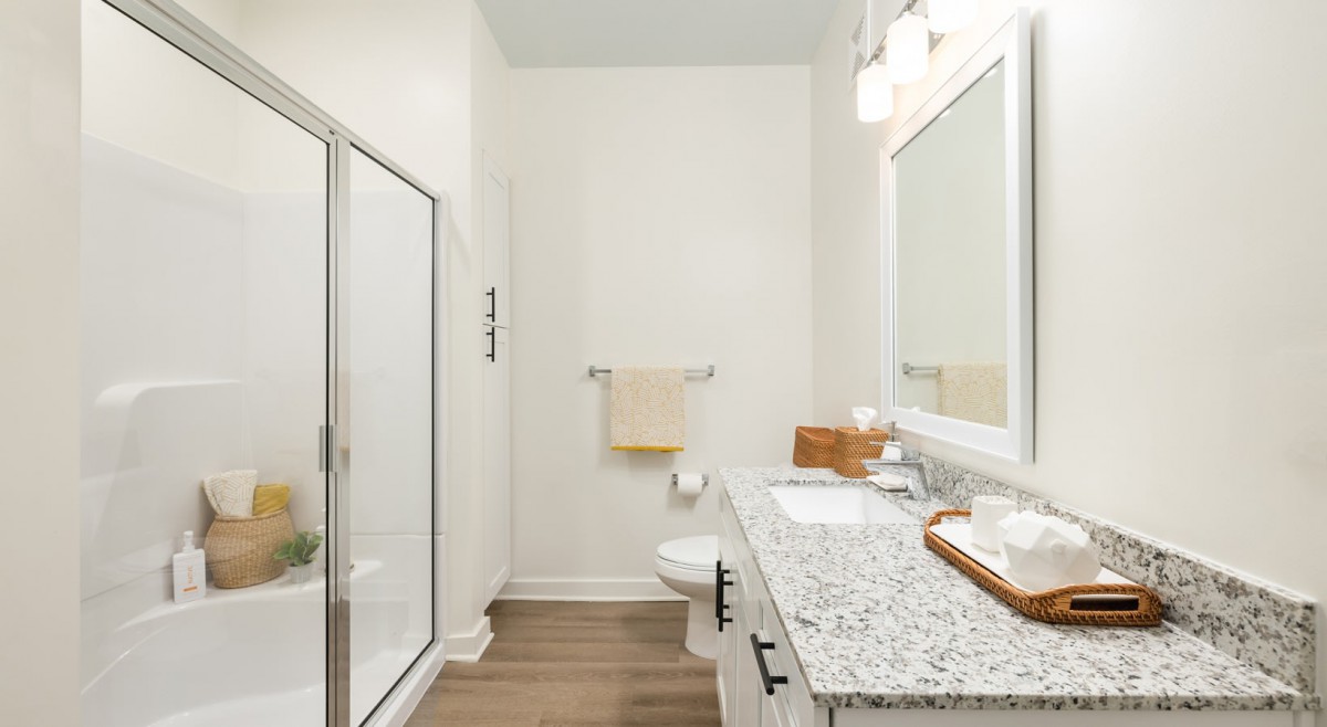 Modern bathroom with glass shower and granite countertop.