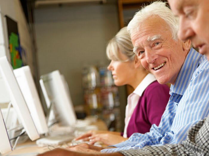 Seniors learning to use computers in a classroom setting.