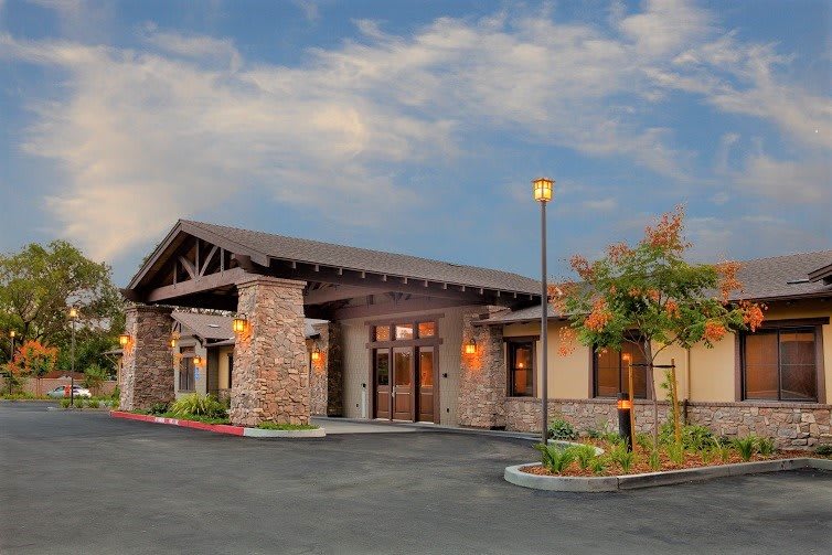 A beautifully lit stone building with a welcoming entrance, set against a cloudy evening sky.