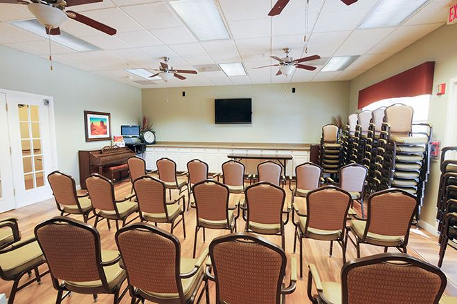 An empty conference room with rows of chairs and a television mounted on the wall.