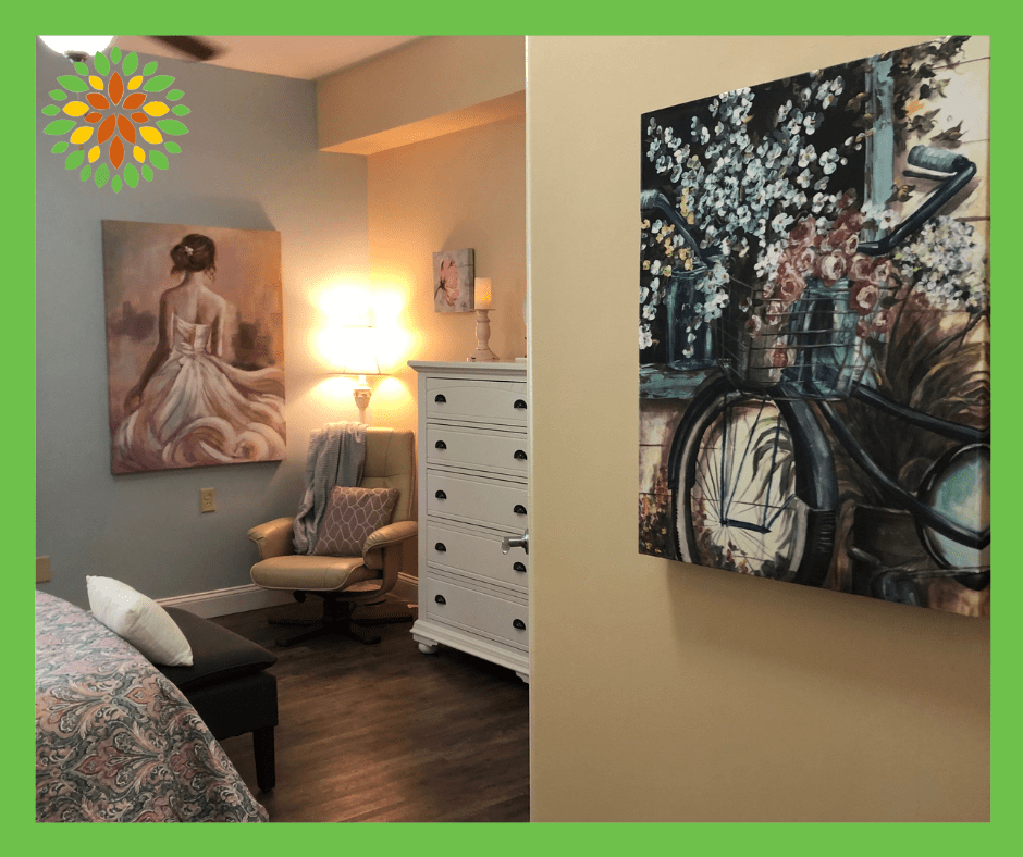 A cozy bedroom featuring elegant artwork, a comfortable chair, and warm lighting.