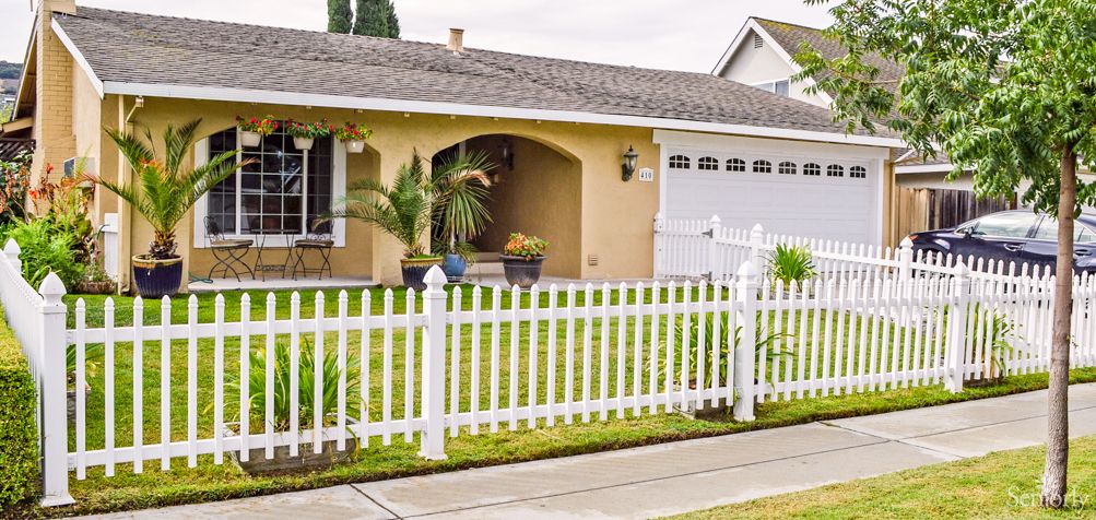 A suburban house with a white picket fence and a well-maintained lawn.