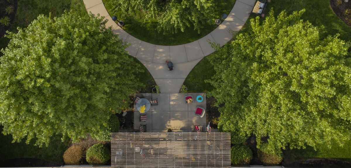 Aerial view of a landscaped area with people walking on a curved pathway surrounded by greenery.