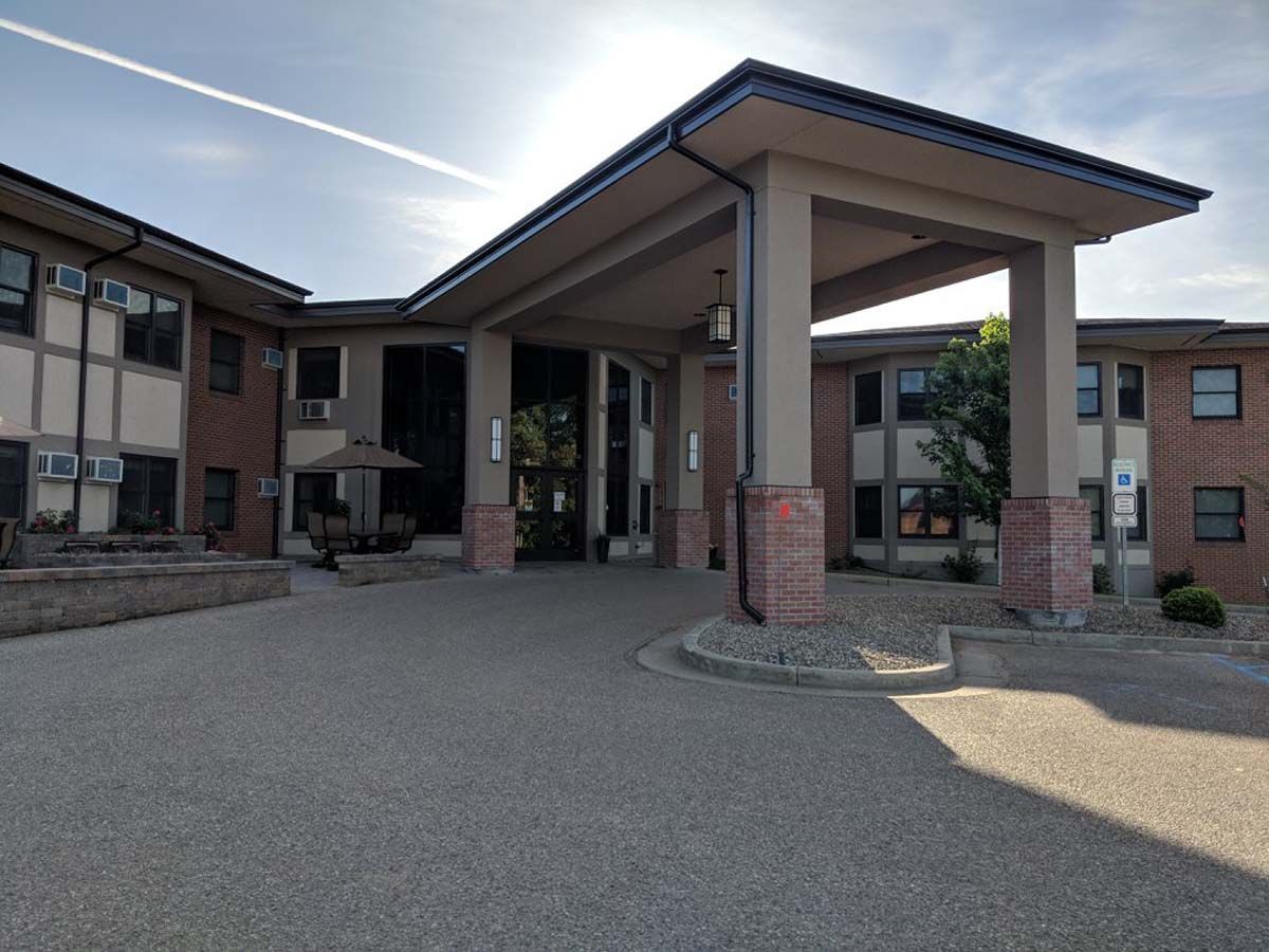 A modern building with a prominent entrance and columns under a clear sky.