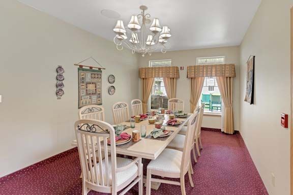 A traditional dining room with a long table, chandelier, and decorative accents.