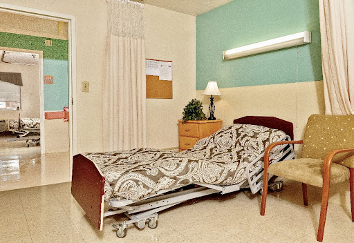 A well-lit hospital room featuring a patient bed and bedside table.