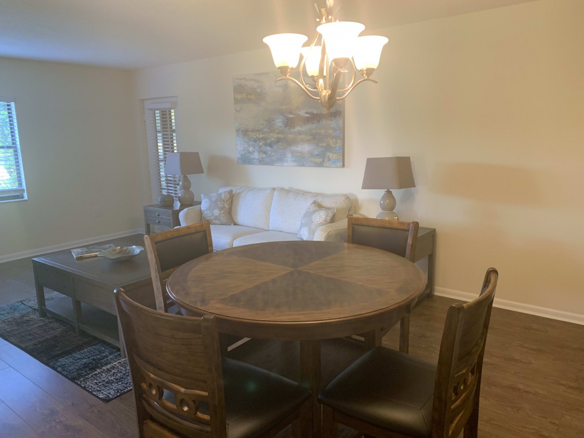 A cozy dining area with a round table, chairs, and a nearby sofa under soft lighting.