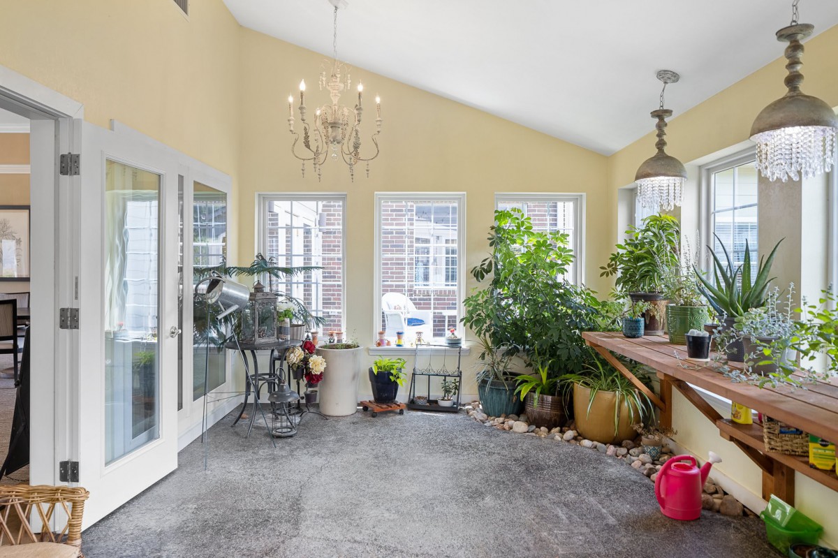 A bright sunroom filled with indoor plants and elegant lighting.