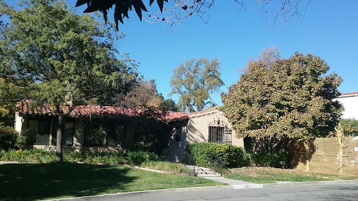 A charming house surrounded by lush greenery and a clear blue sky.