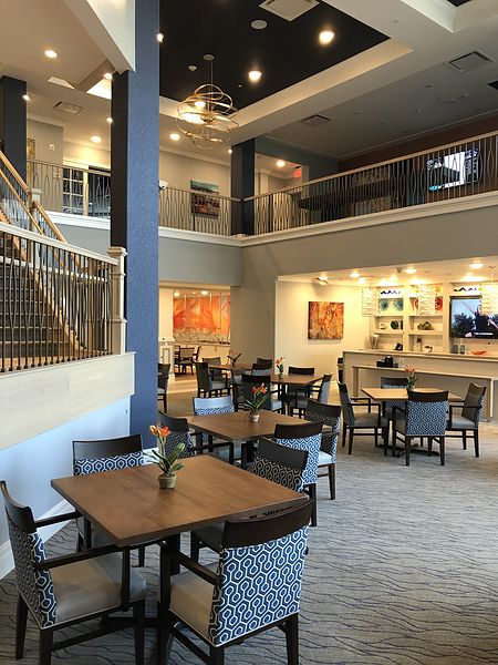 A modern, open-space restaurant with a two-story layout featuring multiple dining tables and comfortable seating.