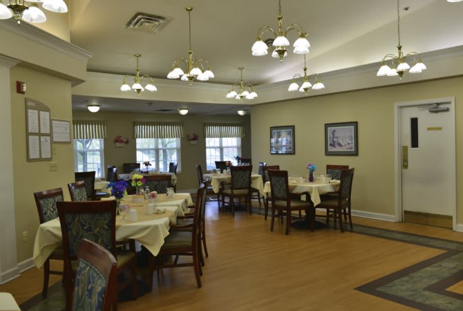 A well-lit dining room with neatly arranged tables and chairs.