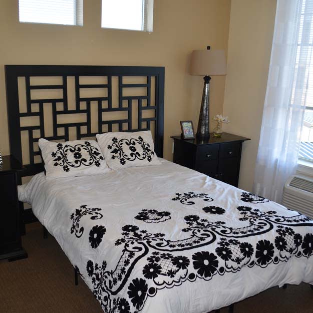 A cozy bedroom with a decorative bedspread and matching pillows, accompanied by a lamp on the nightstand.