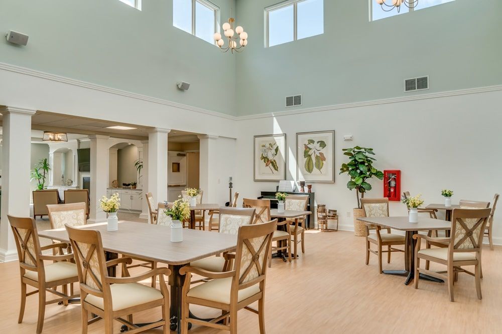 A spacious and well-lit dining area with multiple tables and chairs, decorated with indoor plants and wall art.