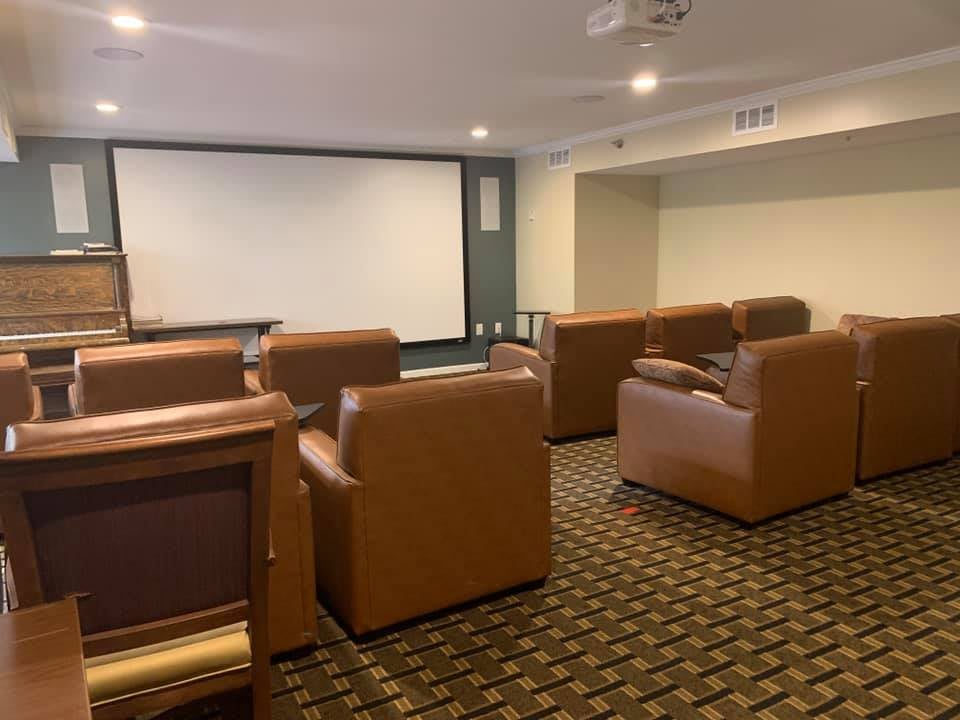 A cozy home theater room with leather seating and a large projector screen.