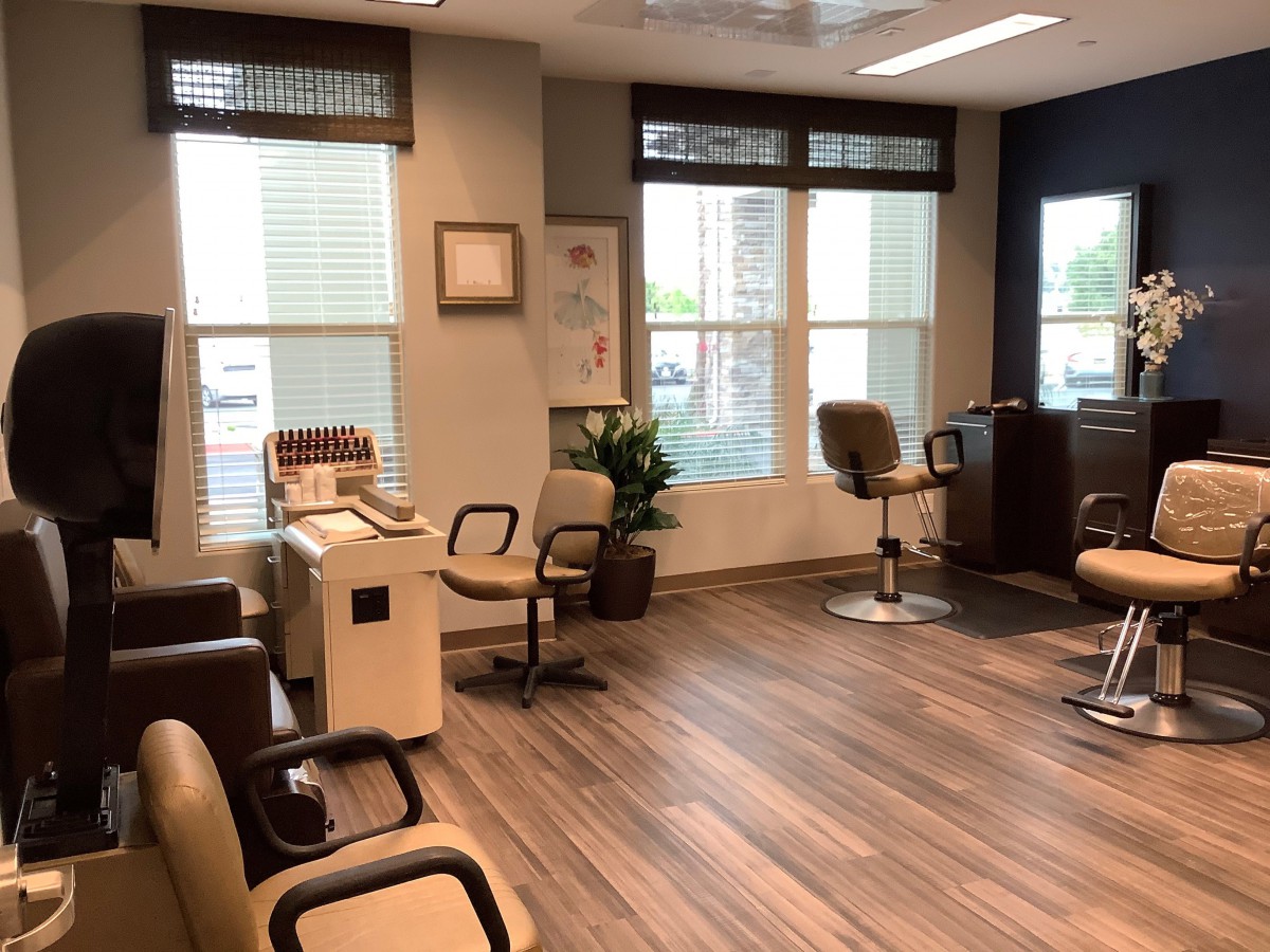 A modern hair salon interior with stylish chairs and large windows.
