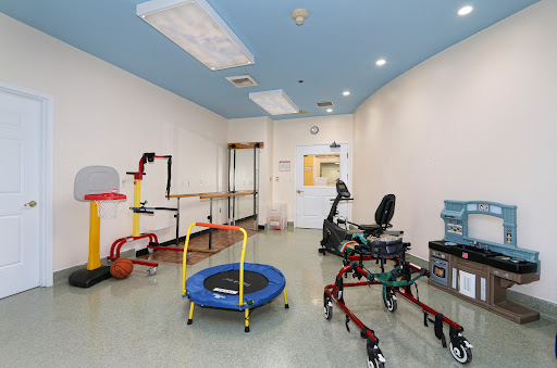 A well-equipped therapy room featuring a trampoline and various rehabilitation tools.