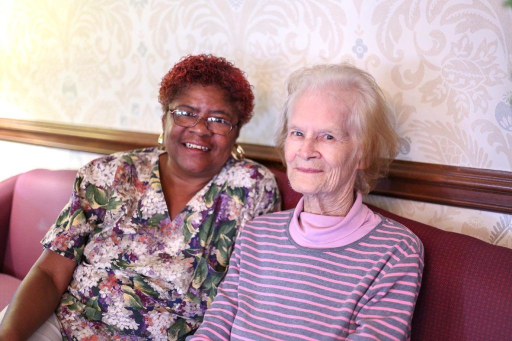 Two elderly women sitting together and smiling.