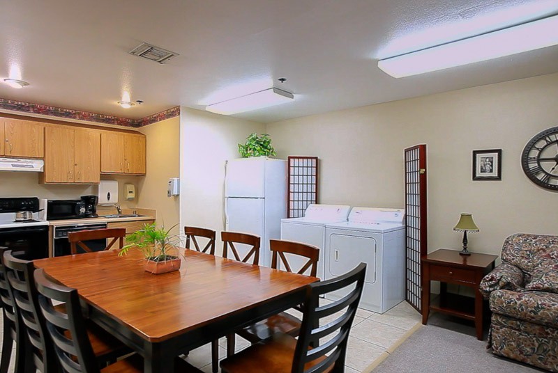 A cozy kitchen and dining area with a wooden table, chairs, and appliances including a refrigerator, washer, and dryer.