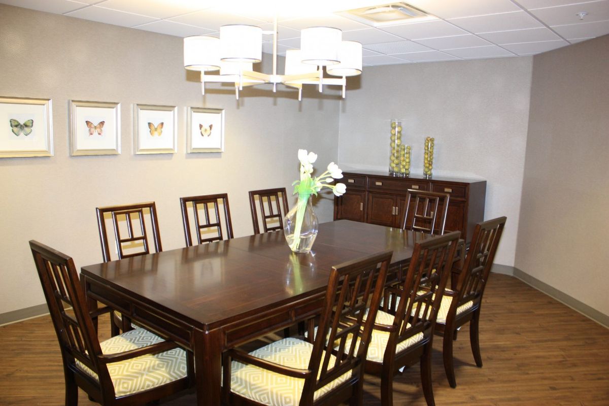 A well-decorated dining room with a large wooden table and chairs set under a modern chandelier.
