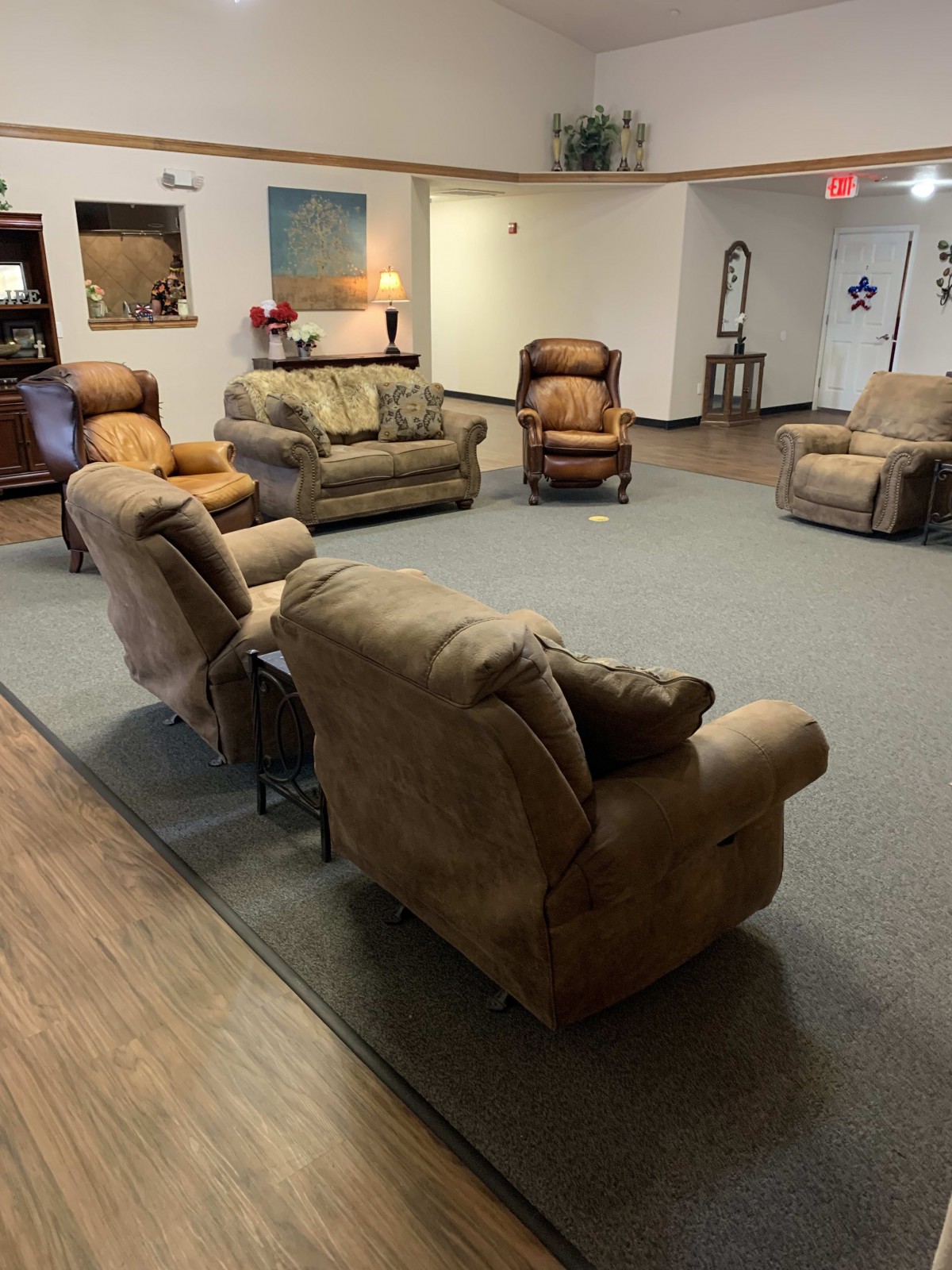A cozy seating area with several armchairs and a sofa arranged in a circle on a carpeted floor.