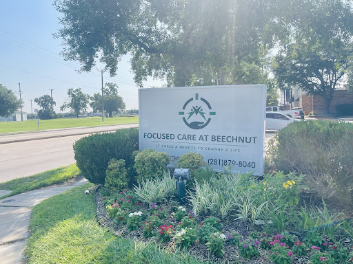A welcoming sign for a healthcare facility, surrounded by greenery and flowers.