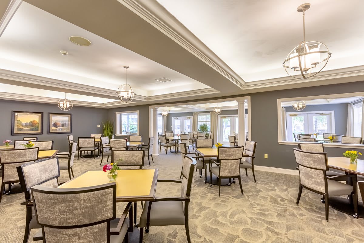 A well-lit dining area with neatly arranged tables and chairs, featuring elegant interior design.