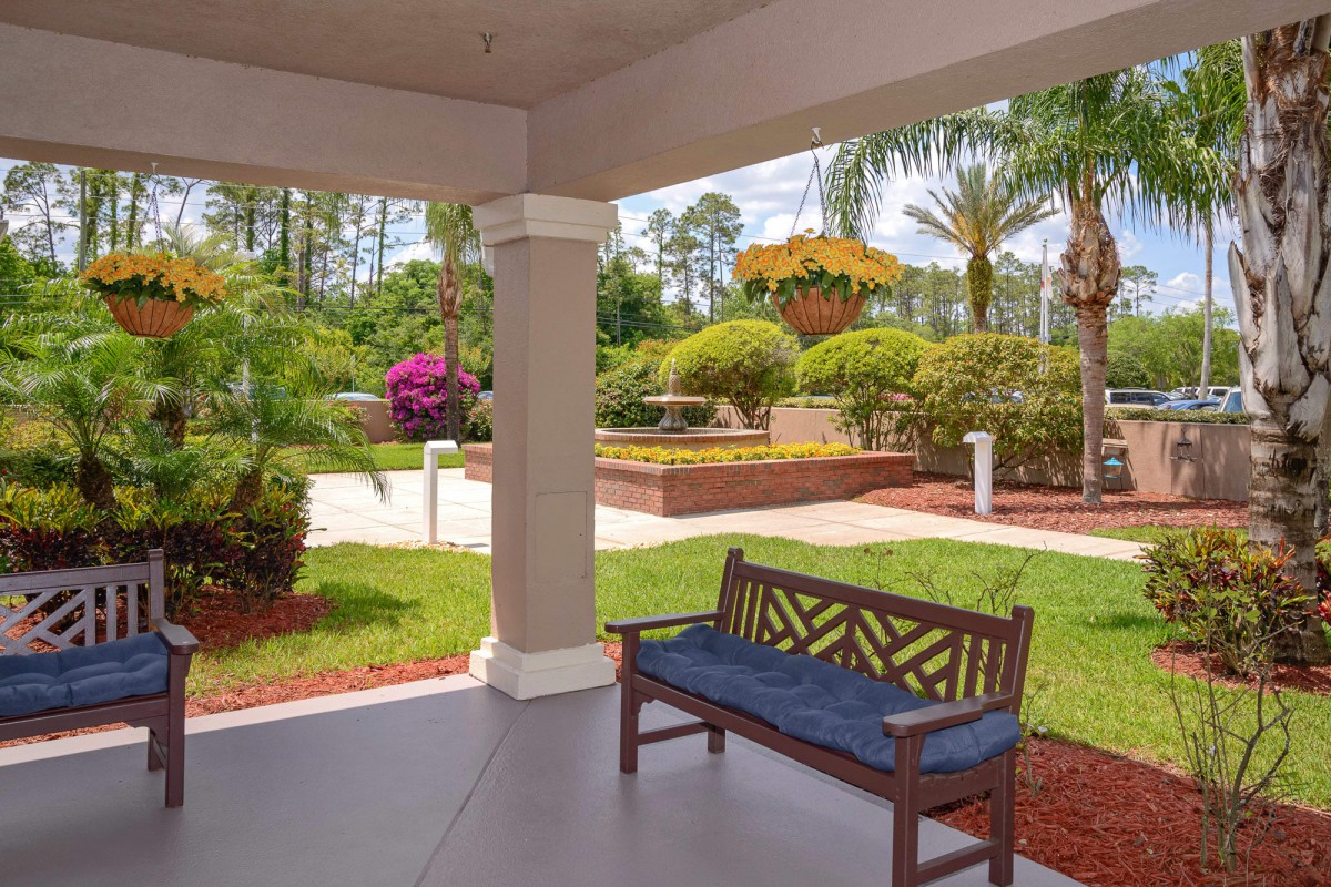 A peaceful patio area with a bench overlooking a beautifully landscaped garden.