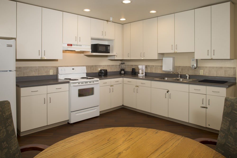 A modern kitchen with white cabinetry and appliances, featuring an oven and microwave.