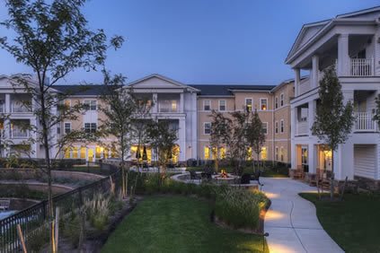 A well-lit residential building with landscaped gardens during the evening.