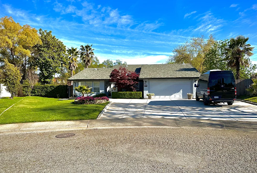 A charming single-story house with a well-maintained front yard and clear blue skies.