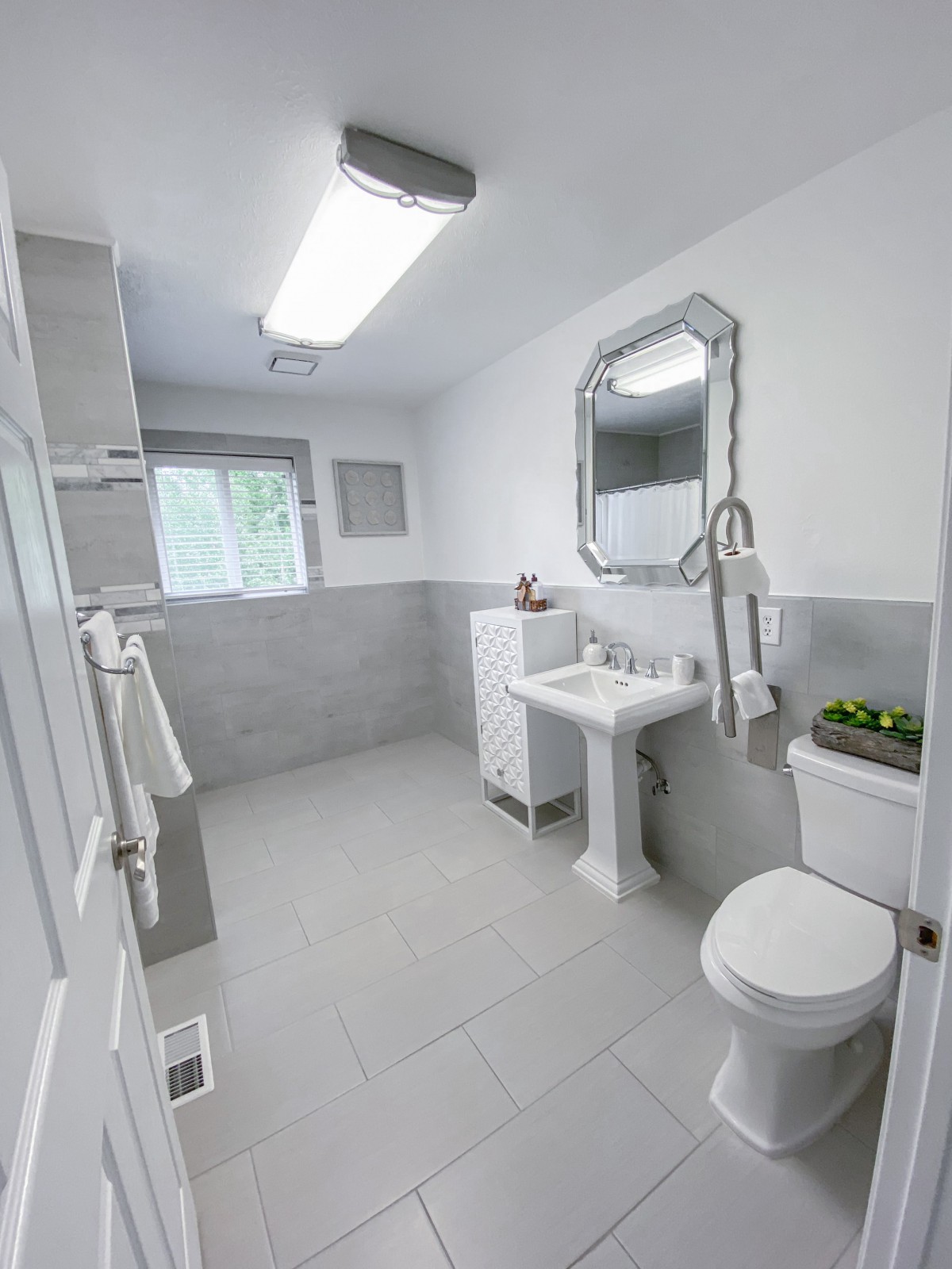A clean and modern bathroom with white tiles and minimalist decor.