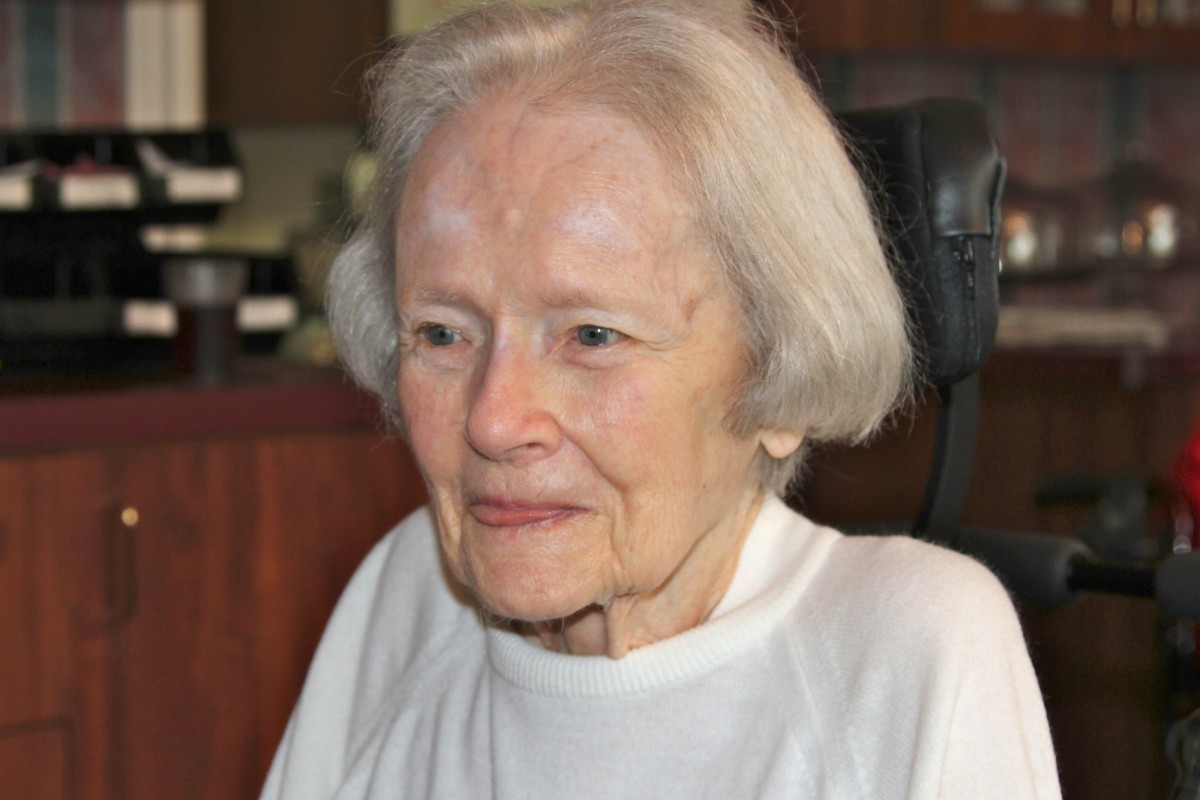 Portrait of an elderly woman with white hair sitting indoors.