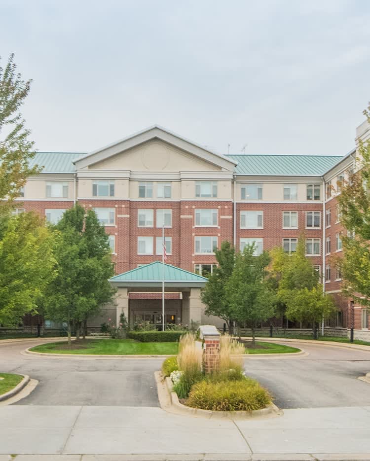 A mid-sized hotel building with a landscaped entrance and surrounding trees.