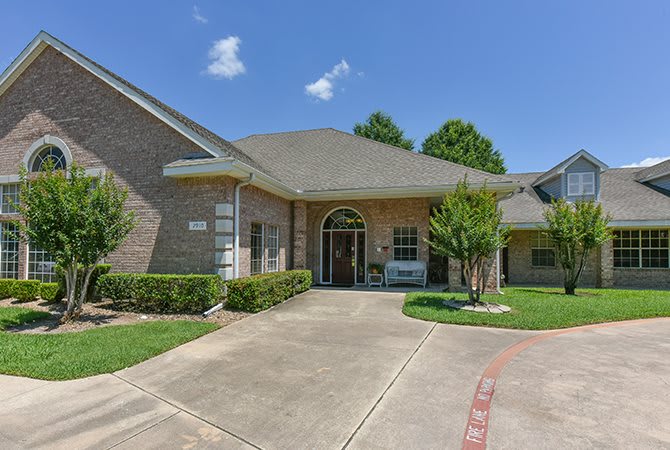 A suburban brick house with a driveway and front yard.