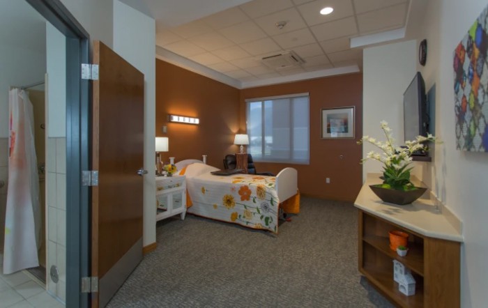 A well-furnished hospital room with a bed, lamps, and a window.