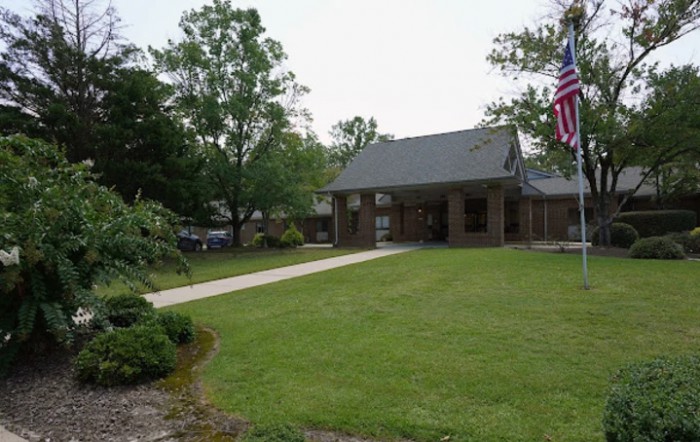 A suburban house with a well-maintained lawn and an American flag displayed in the front yard.