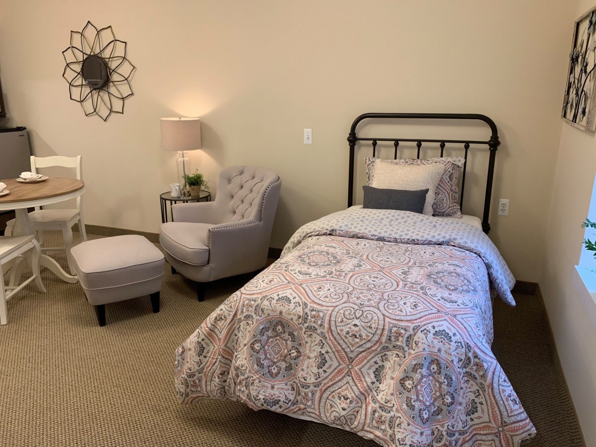 A cozy bedroom with a single bed and an armchair.
