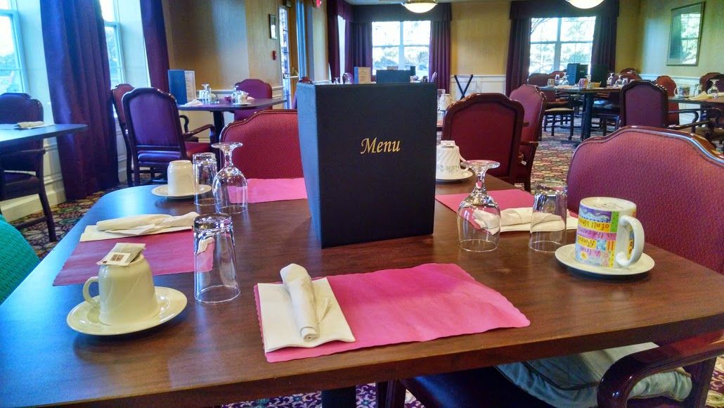 An elegantly set restaurant table with a menu and neatly arranged glassware and napkins.