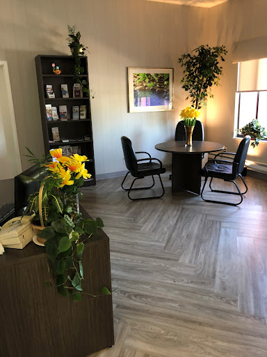 A cozy office space designed for meetings, featuring a round table, comfortable chairs, and greenery.
