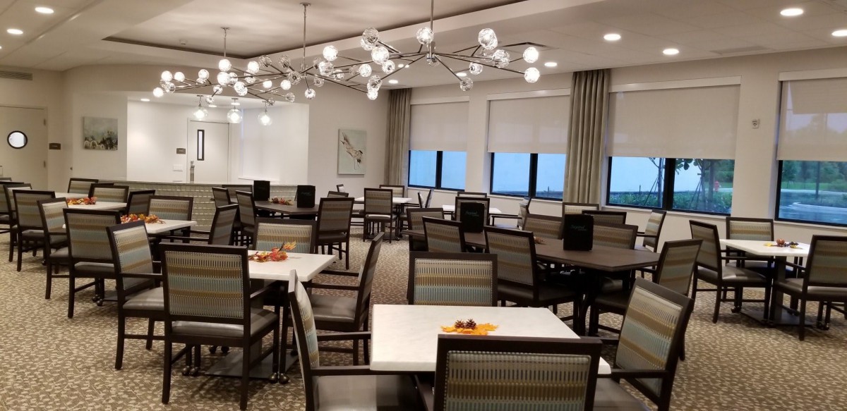A modern dining area with neatly arranged tables and chairs under stylish lighting.