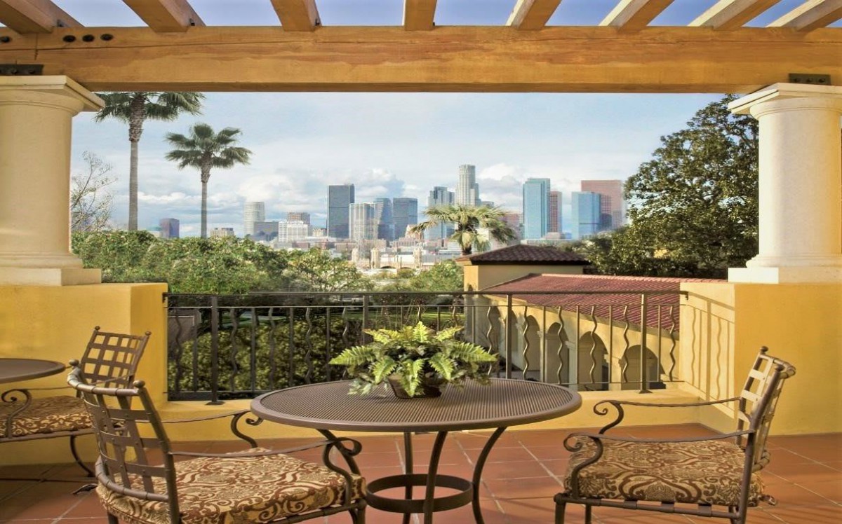 A patio with a table and chairs offers a stunning view of the city skyline in the background.