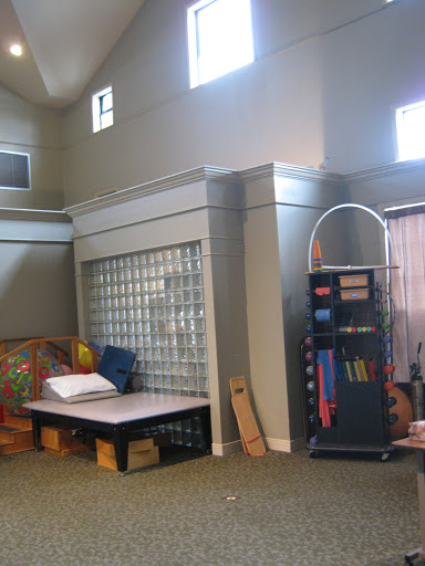 A spacious play area featuring a glass block wall, various furniture pieces, and educational materials.