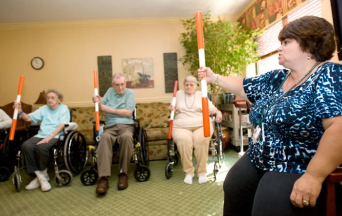 Seniors participating in a group exercise session with orange and white rods.