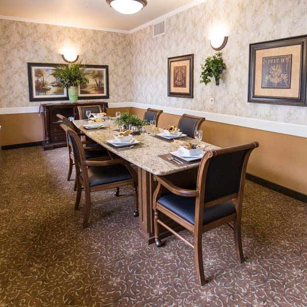 A well-decorated dining room with a large table and stylish chairs, adorned with plants and artwork.