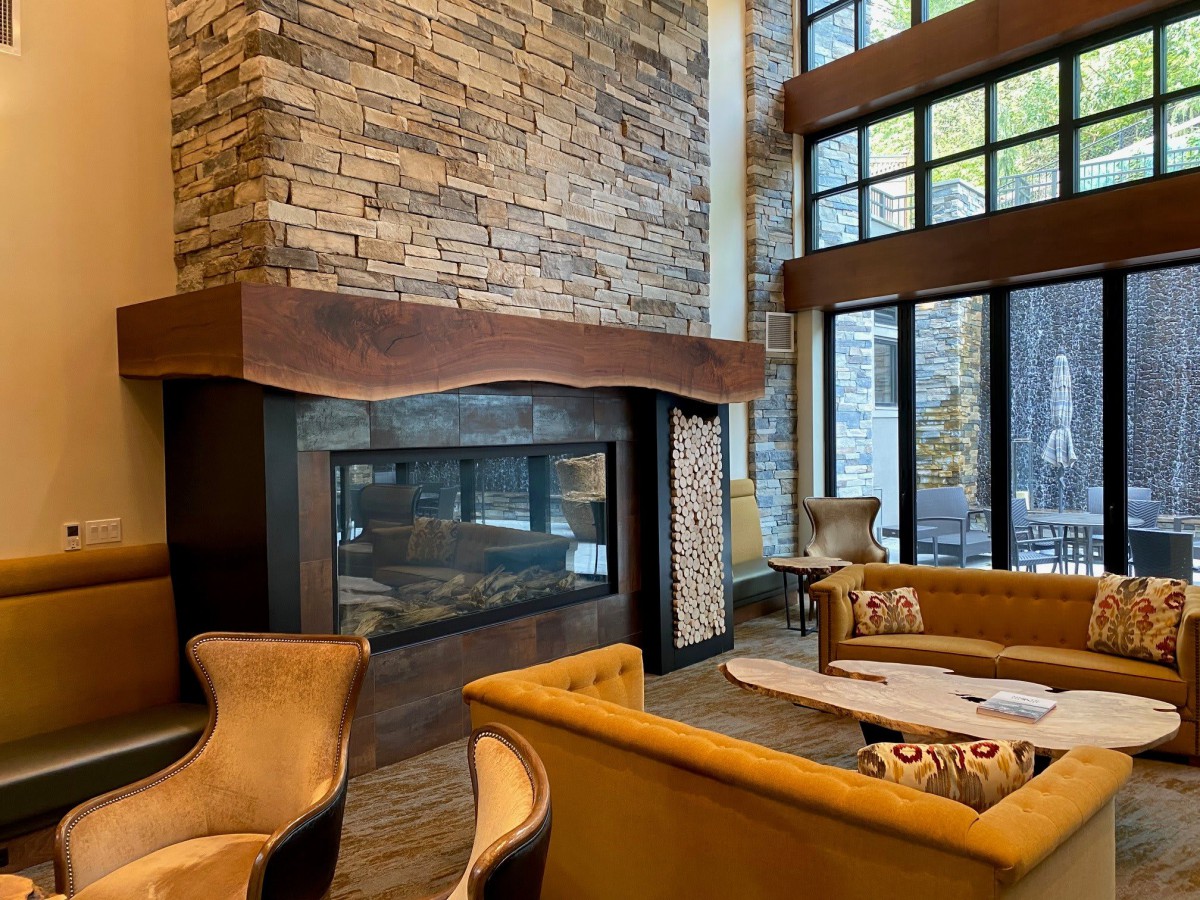 A cozy lounge with a modern stone fireplace and large windows.