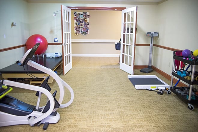 A small gym space equipped with various exercise machines and an exercise ball.